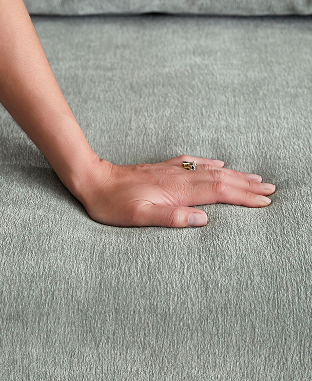 A hand is pressing down on the sofa bed's green surface. A hand is pressing down on the sofa bed's green surface.