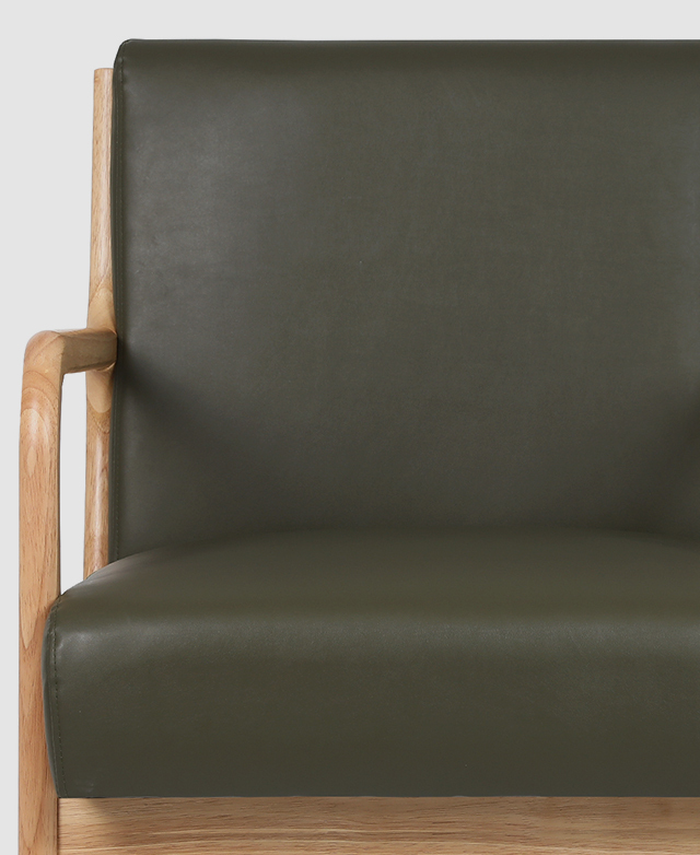 A front-on view of the green armchair displays the smooth finish of the faux leather upholstery.