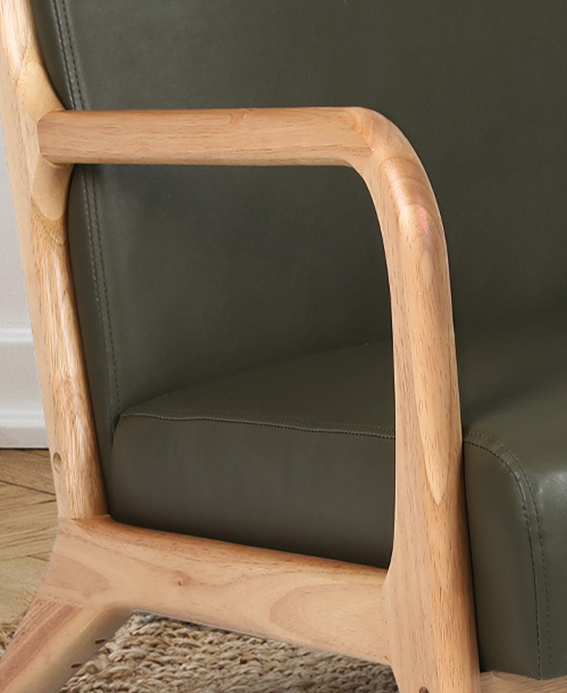 A close view of an armrest of the green armchair highlights its rich tones, natural grains, and smooth finish.