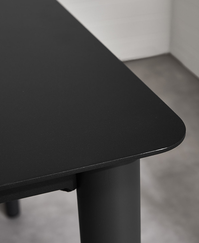 One of the rounded corners of the black dining table is shown. One of the rounded corners of the black dining table is shown.