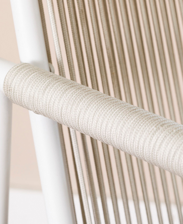 Off-white polyester rope is wrapped around the outdoor dining chair's armrest.