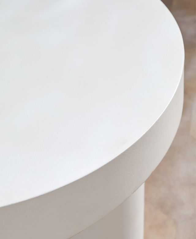 The thick, round white table top is shown from a bird's eye view close up. The thick, round white table top is shown from a bird's eye view close up.