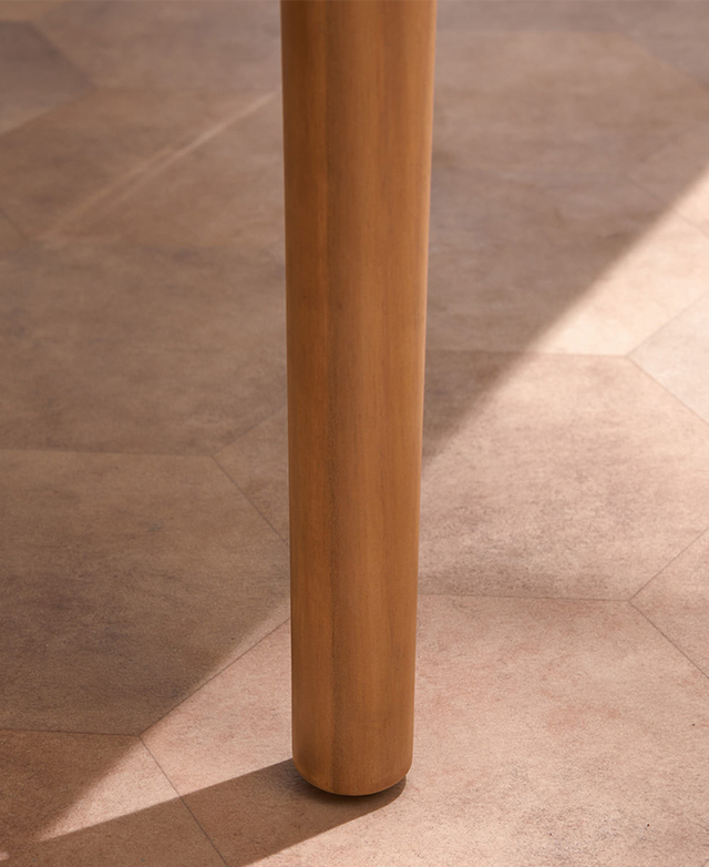One of the slightly tapered acacia wood legs is shown on a clay-coloured tiled floor. One of the slightly tapered acacia wood legs is shown on a clay-coloured tiled floor.
