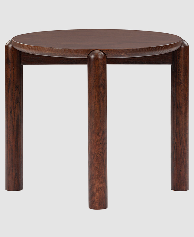 A walnut side table is shown from the side, front-on, to highlight its simple silhouette and and strong cylindrical legs. A walnut side table is shown from the side, front-on, to highlight its simple silhouette and and strong cylindrical legs.