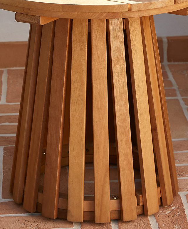 The vertical slatting of the eucalyptus pillar base is on a red brick floor. The vertical slatting of the eucalyptus pillar base is on a red brick floor.