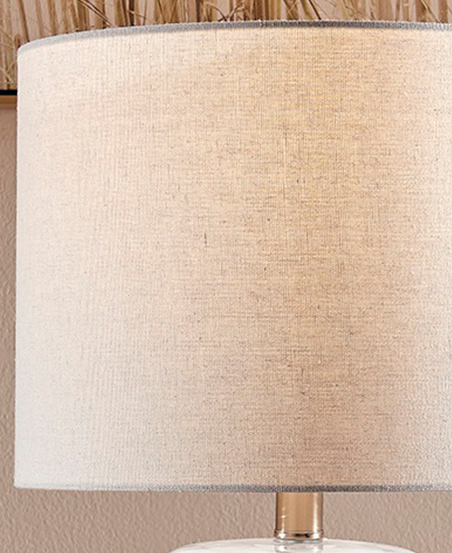 An off-white fabric drum shade is illuminated by a hidden bulb.