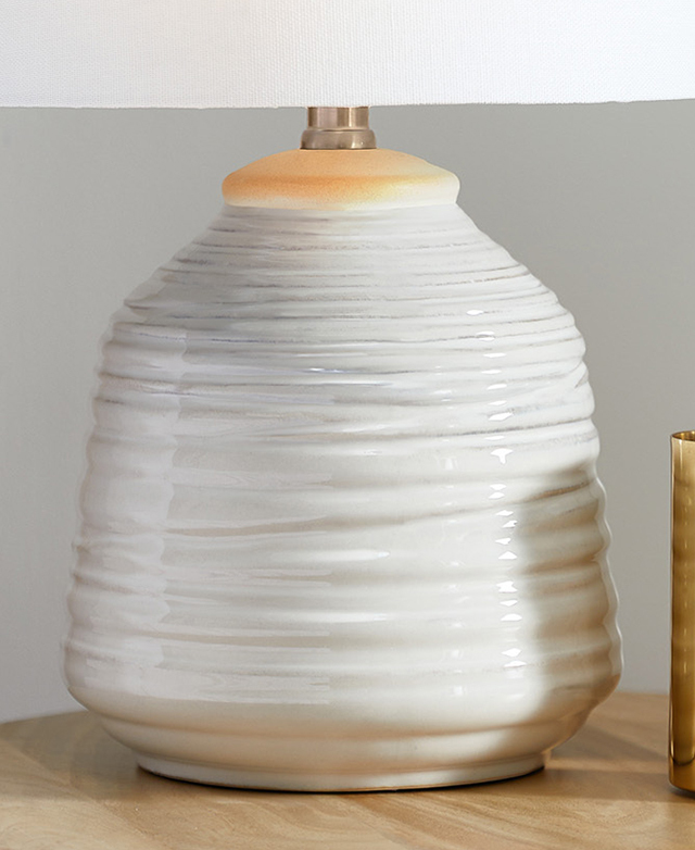The white ceramic lamp base has a textured, spun design that gives irregular concentric circles on its surface. The white ceramic lamp base has a textured, spun design that gives irregular concentric circles on its surface.