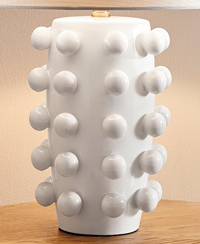 Striking white ceramic lamp base with all over protruding ceramic knobs. It's on a timber surface.
