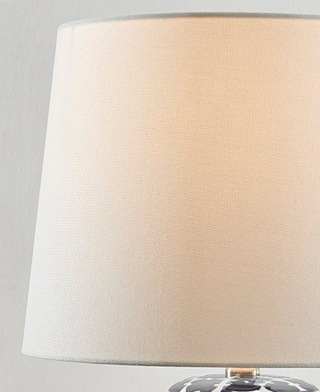 A slightly tapered white fabric shade is illuminated by a hidden bulb. A slightly tapered white fabric shade is illuminated by a hidden bulb.