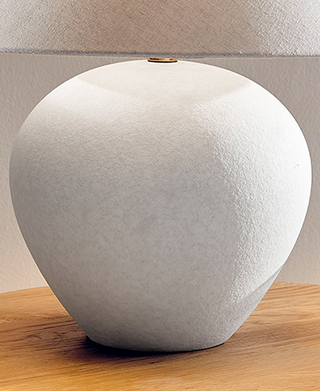The large, bulbous white lamp base has a subtly textured finish. It sits on a wooden surface.