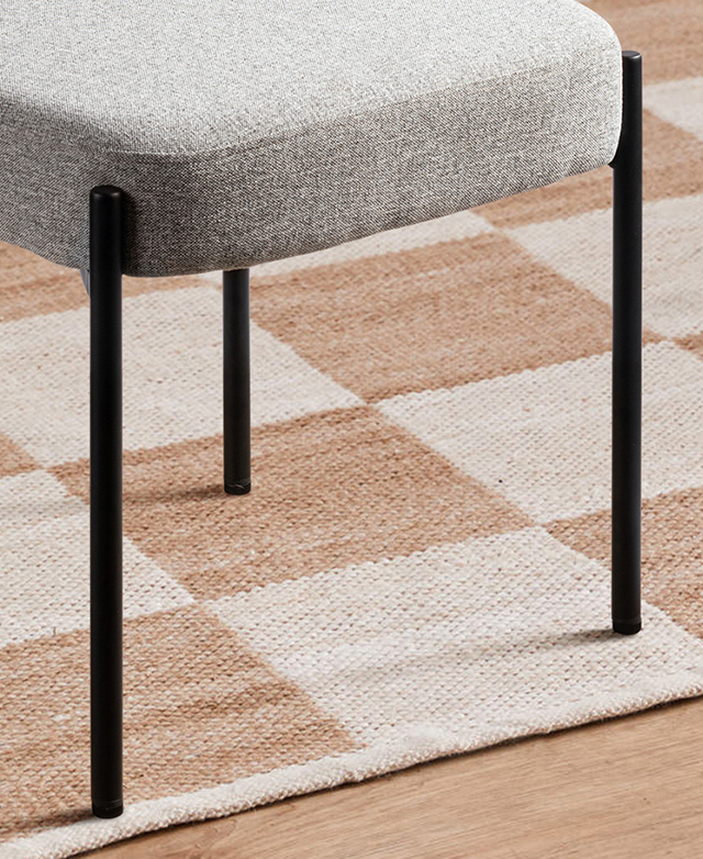 The grey chair is on a taupe and green checkered rug; the sleek, slender, black metal legs are powder coated. The grey chair is on a taupe and green checkered rug; the sleek, slender, black metal legs are powder coated.