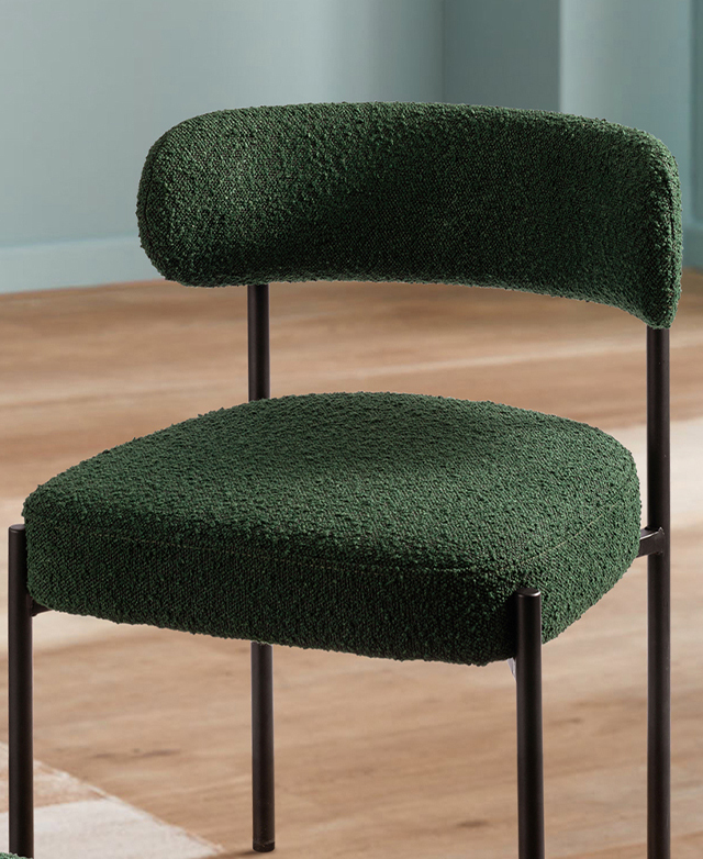 The rich green dining chair is upholstered with textured boucle fabric on the seat and the backrest. The rich green dining chair is upholstered with textured boucle fabric on the seat and the backrest.