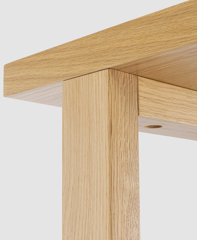 The oak wood veneer is zoomed in on via an upper leg and under a shelf to display its quality and wood grain effect.