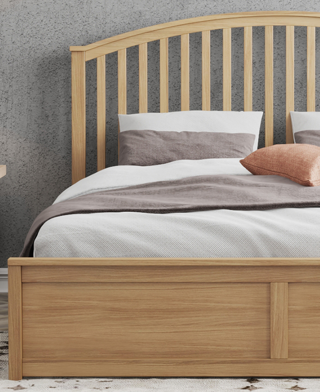 The arched pine wood bedhead is flush against a grey wall, and the bed is dressed with cream and grey bedding. The arched pine wood bedhead is flush against a grey wall, and the bed is dressed with cream and grey bedding.