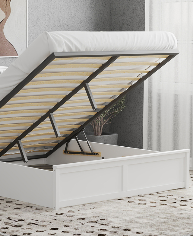 The white bed is shown in a bedroom with a mattress on top, elevated on its slats to reveal the storage space beneath. The white bed is shown in a bedroom with a mattress on top, elevated on its slats to reveal the storage space beneath.