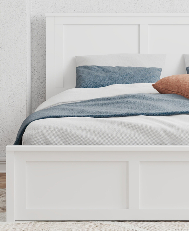 The white panelled bed frame is in front of a speckled white wall, and the bed is dressed with white and blue bedding. The white panelled bed frame is in front of a speckled white wall, and the bed is dressed with white and blue bedding.