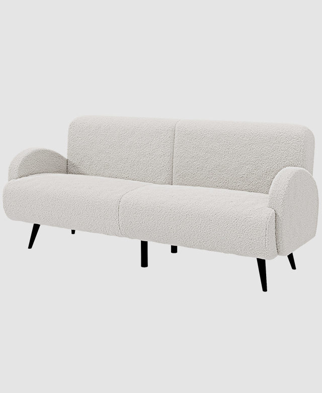 A full view of the cream sofa at a three-quarter angle shows the slender silhouette and textured upholstery.