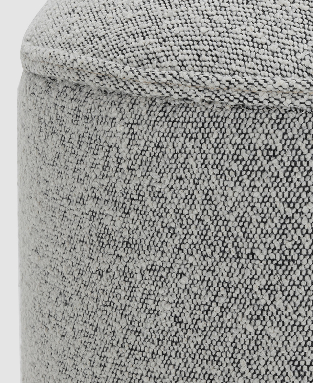 The two-tone cream and black boucle fabric and the corded piping trim adorn the end of the ottoman. The two-tone cream and black boucle fabric and the corded piping trim adorn the end of the ottoman.