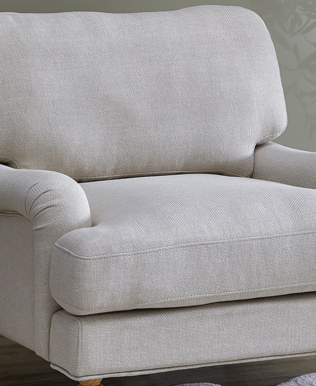 The generously-filled seat and backrest of the wide, oat-coloured armchair are emphasised with a cropped view. The generously-filled seat and backrest of the wide, oat-coloured armchair are emphasised with a cropped view.