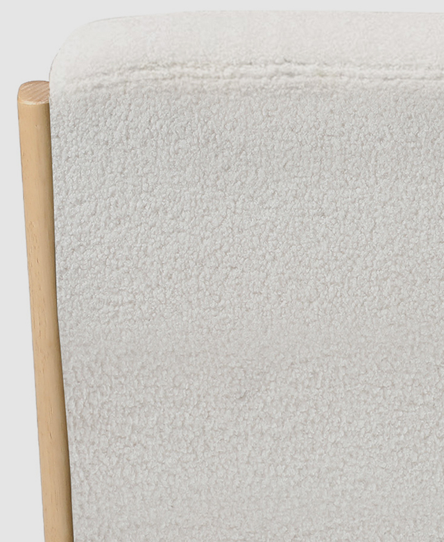 Cropped view of the back of the armchair highlights the plush, looped texture of the cream boucle upholstery.