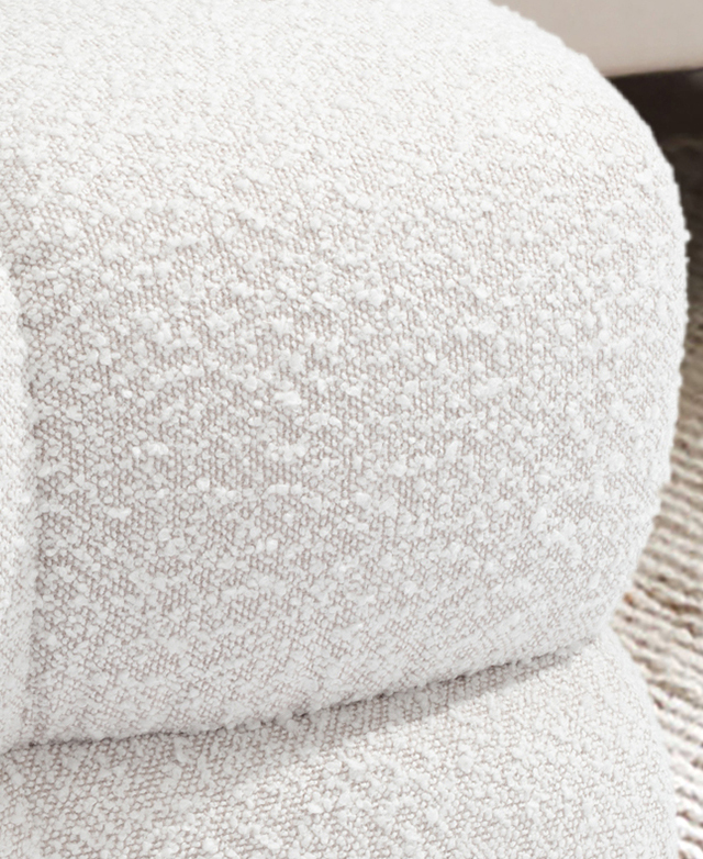 Close up of the creamy nubby texture of boucle upholstery on the ottoman.