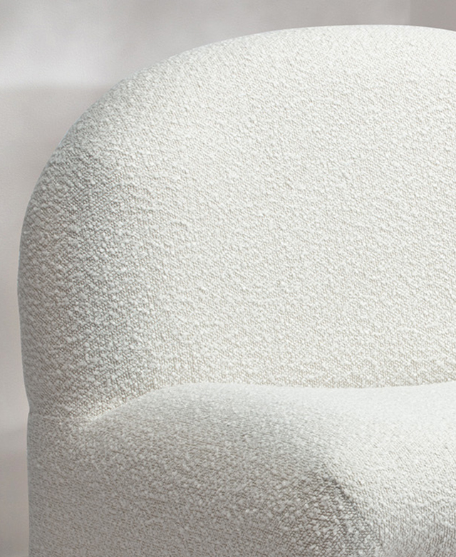 Close up of the creamy nubby texture of boucle upholstery on the accent chair.