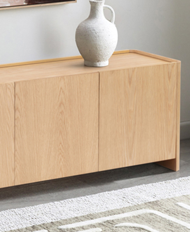 A white textured jug is on top of an oak-coloured TV unit, with a creamy rug in front of it.