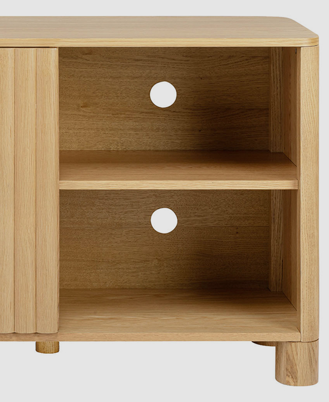 One end of the sideboard is shown with its door open, revealing two cable holes above each shelf within.