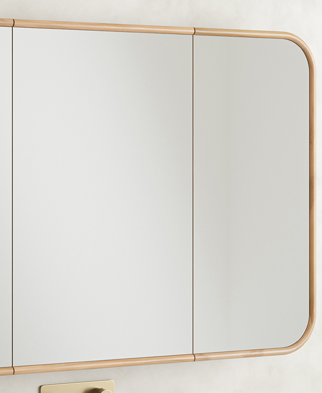 The wide, rectangular, mirrored cabinet is positioned on a concrete-look wall.