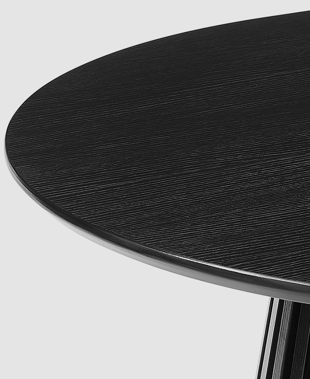 One end of the black dining table is zoomed in on to highlight the smooth surfaces and the bevelled edge.