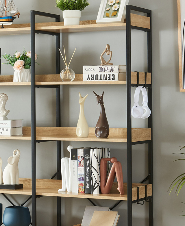 An angled view of the bookshelf shows the hooks at the ends with headphones hanging, and shelves filled with decor. An angled view of the bookshelf shows the hooks at the ends with headphones hanging, and shelves filled with decor.