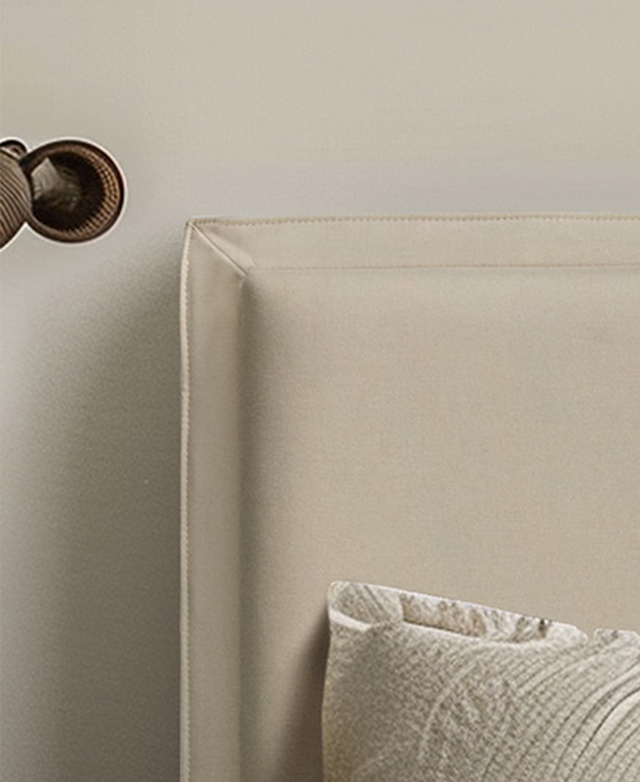 Close-up view of the cream bedhead against an off-white wall, highlighting the thick French seam.
