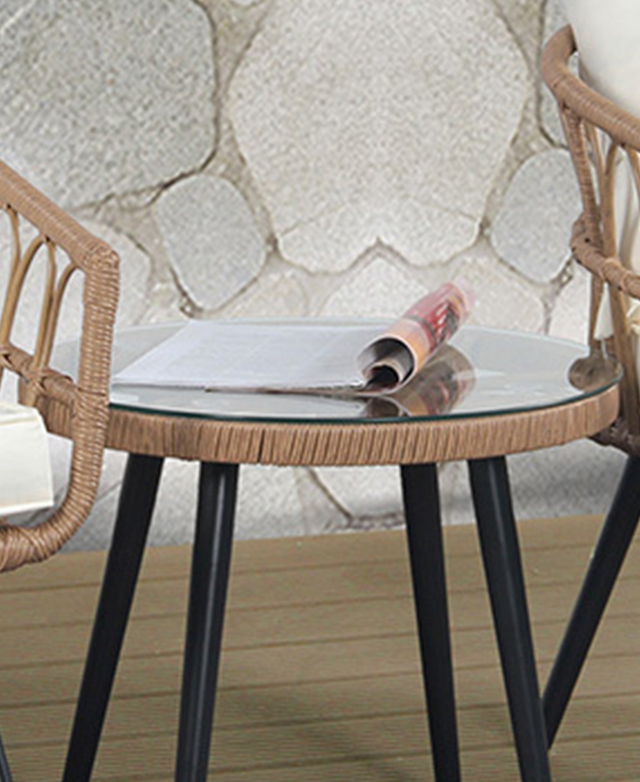 The glass-topped round side table has a folded-back magazine on top. The glass-topped round side table has a folded-back magazine on top.