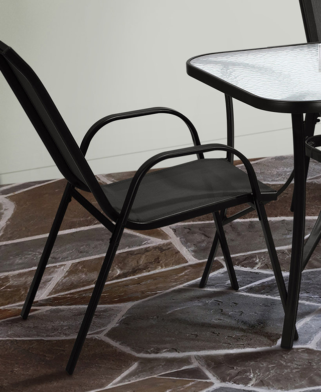A rounded, U-shaped black metal armrest-cum-leg structure is in focus, and positioned next to a dining table. A rounded, U-shaped black metal armrest-cum-leg structure is in focus, and positioned next to a dining table.