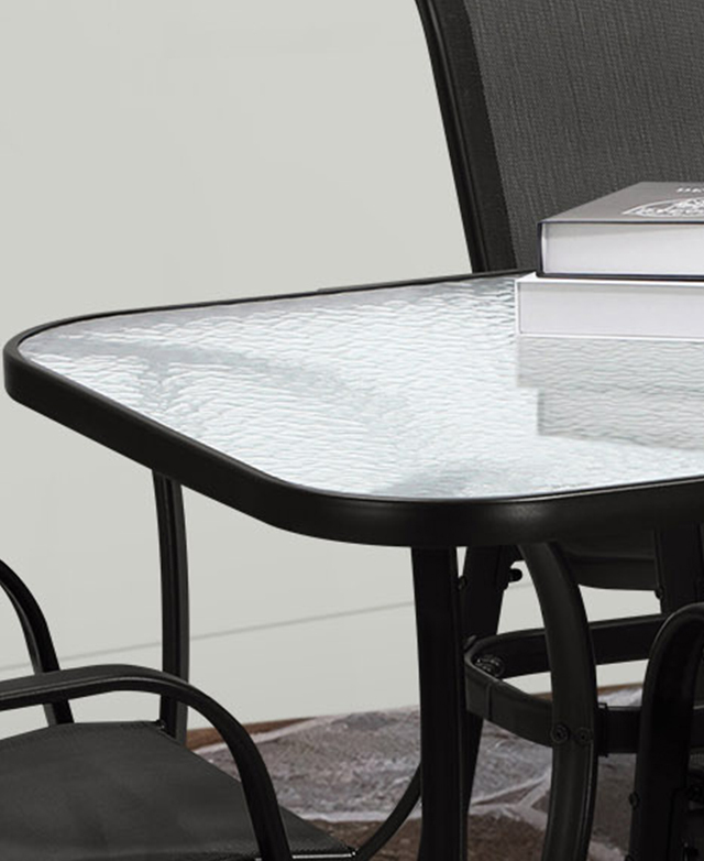 The smooth glass table top has a dimpled-effect and a black metal frame. A stack of books is on top. The smooth glass table top has a dimpled-effect and a black metal frame. A stack of books is on top.