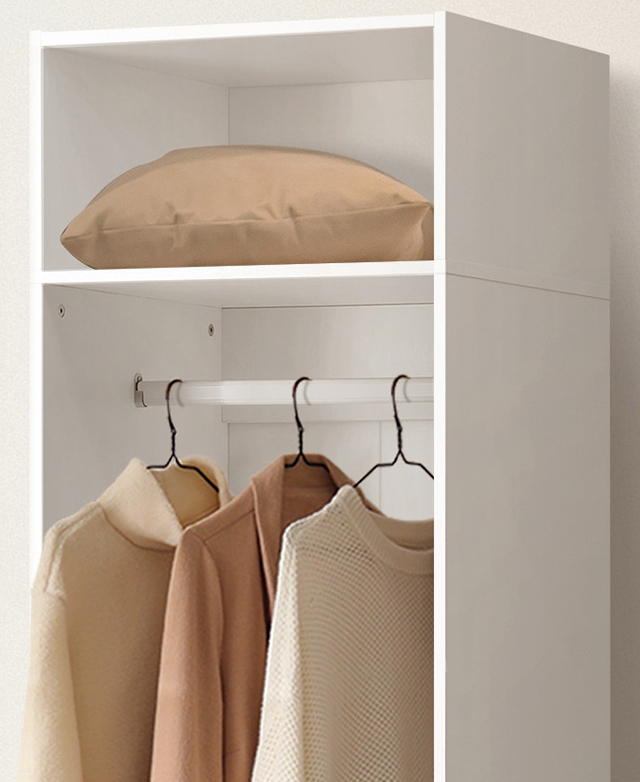 The top half of the wardrobe is shown with with a cushion on the top shelf and neutral clothes hanging inside.