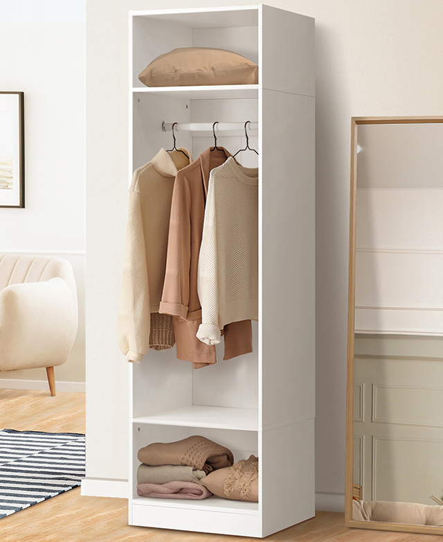 The full wardrobe's door is open and it's filled with hung and folded clothes. A mirror leans against the wall next to it.