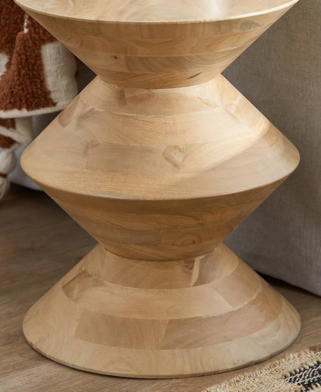 Close up of the side table's base, which has a sculptural form and is made from warm-hued mango wood.