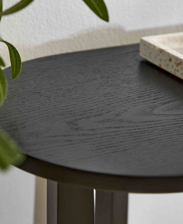 Close up of the rounded top of the black console table highlights its textural natural veining. Close up of the rounded top of the black console table highlights its textural natural veining.