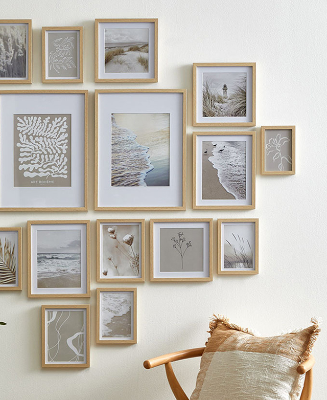 Various shapes and sizes of wood-look frames are filled with nature images and hung on a white wall.