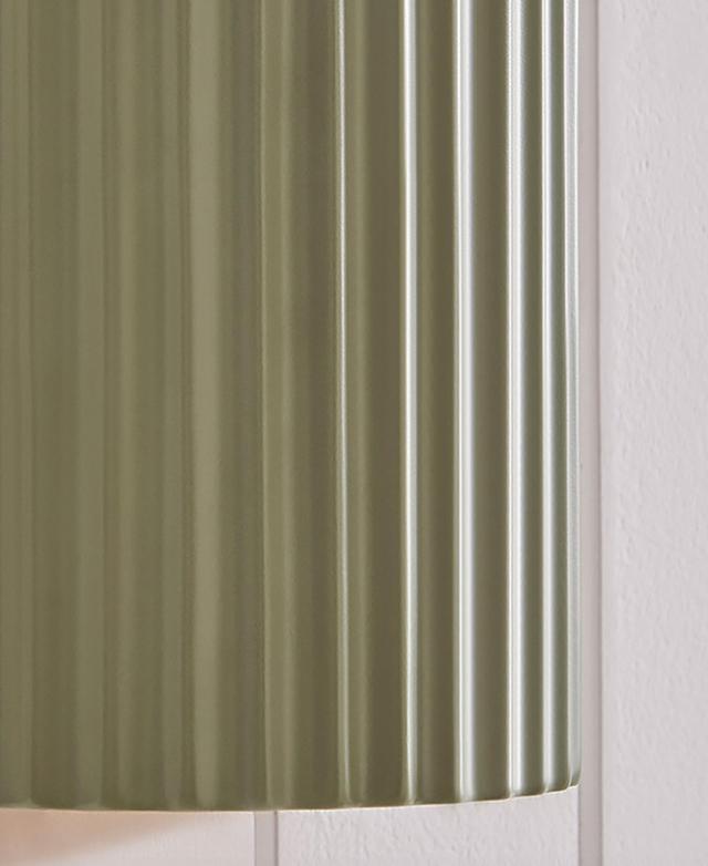 A close up of the green, fluted ceramic wall light highlights its texture. A close up of the green, fluted ceramic wall light highlights its texture.