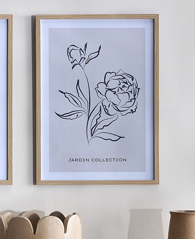 A black floral line drawing on a taupe background is in a 'natural' frame and hung on a white wall.