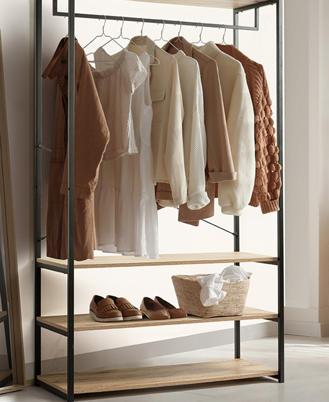 The black-framed clothing rack is positioned in a room, with clothes hanging, and items on a lower shelf. The black-framed clothing rack is positioned in a room, with clothes hanging, and items on a lower shelf.