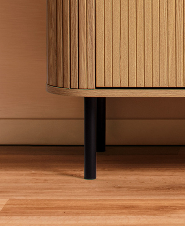 Slim, black cyclindrical metal legs support the chest atop a timber floor.