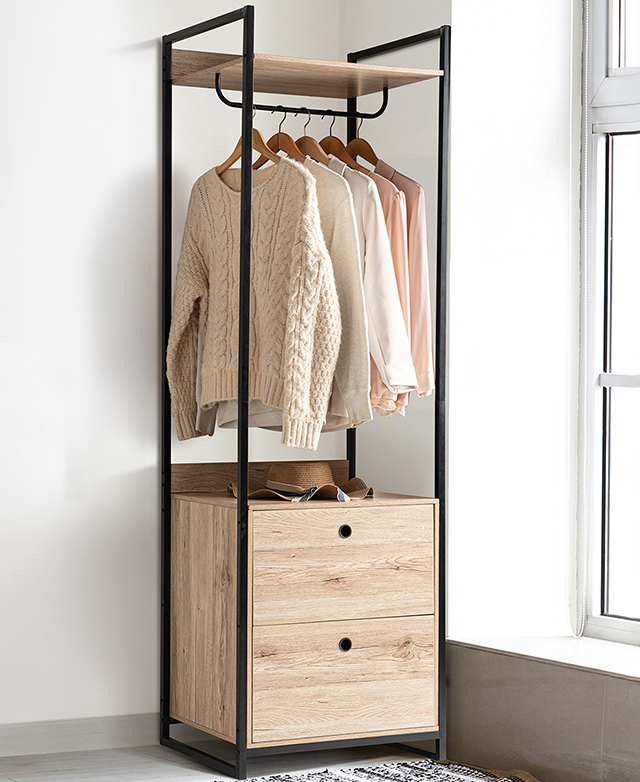 A full black-framed open wardrobe has clothes on the hanging rail and a straw hat on the shelf. A full black-framed open wardrobe has clothes on the hanging rail and a straw hat on the shelf.