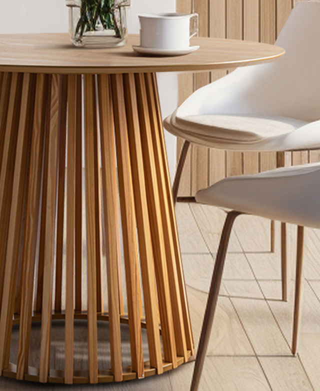 The slatted, tapering pedestal base of the light timber dining table has chairs around it. The slatted, tapering pedestal base of the light timber dining table has chairs around it.