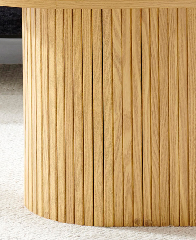 The blocky, light timber coffee table has fluting all around its pedestal base.