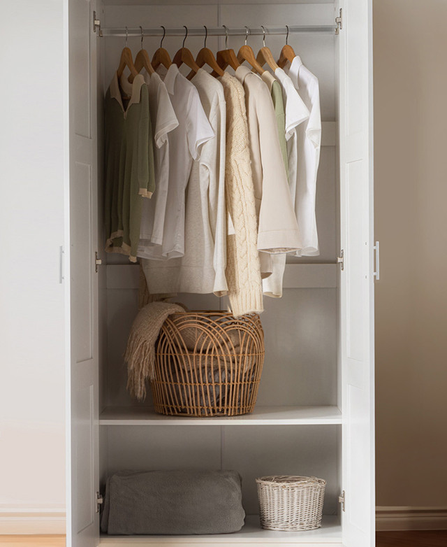 The wardrobe doors are open to reveal clothes on the hanging rack, and baskets and a blanket on the shelves. The wardrobe doors are open to reveal clothes on the hanging rack, and baskets and a blanket on the shelves.