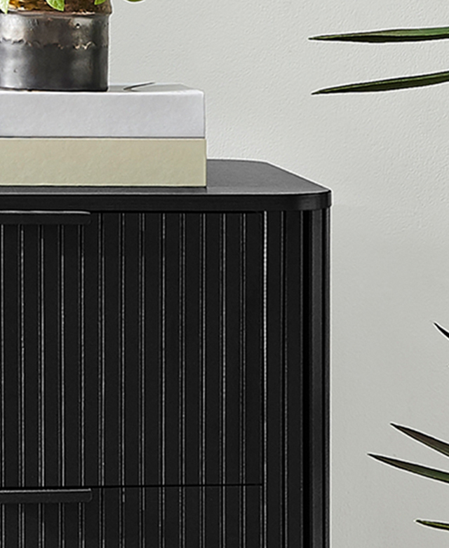 A top corner of the chest of drawers is displayed to highlight the rounded corner; decorative accents are styled on top. A top corner of the chest of drawers is displayed to highlight the rounded corner; decorative accents are styled on top.