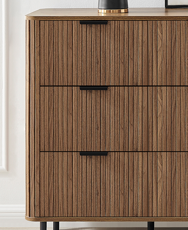 A front view of the walnut-toned chest of drawers displays the beautiful vertical fluting. A front view of the walnut-toned chest of drawers displays the beautiful vertical fluting.
